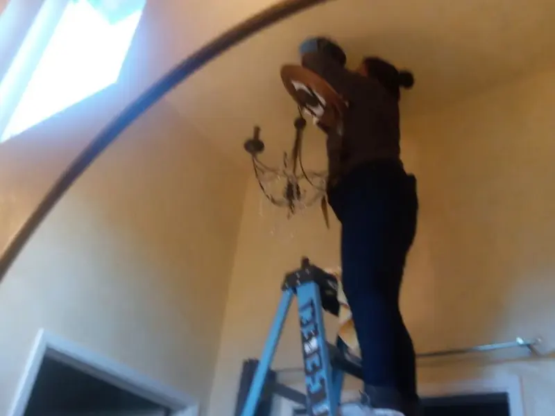 Electrician installing a chandelier in a Almena residence